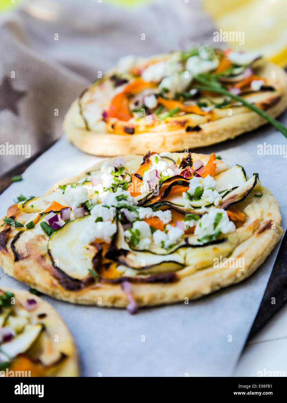 Mini pizza végétarienne avec une croûte dorée surmontée de l'aubergine, le fromage, les herbes et les poivrons disposés en une rangée dans un restaurant ou à emporter Banque D'Images
