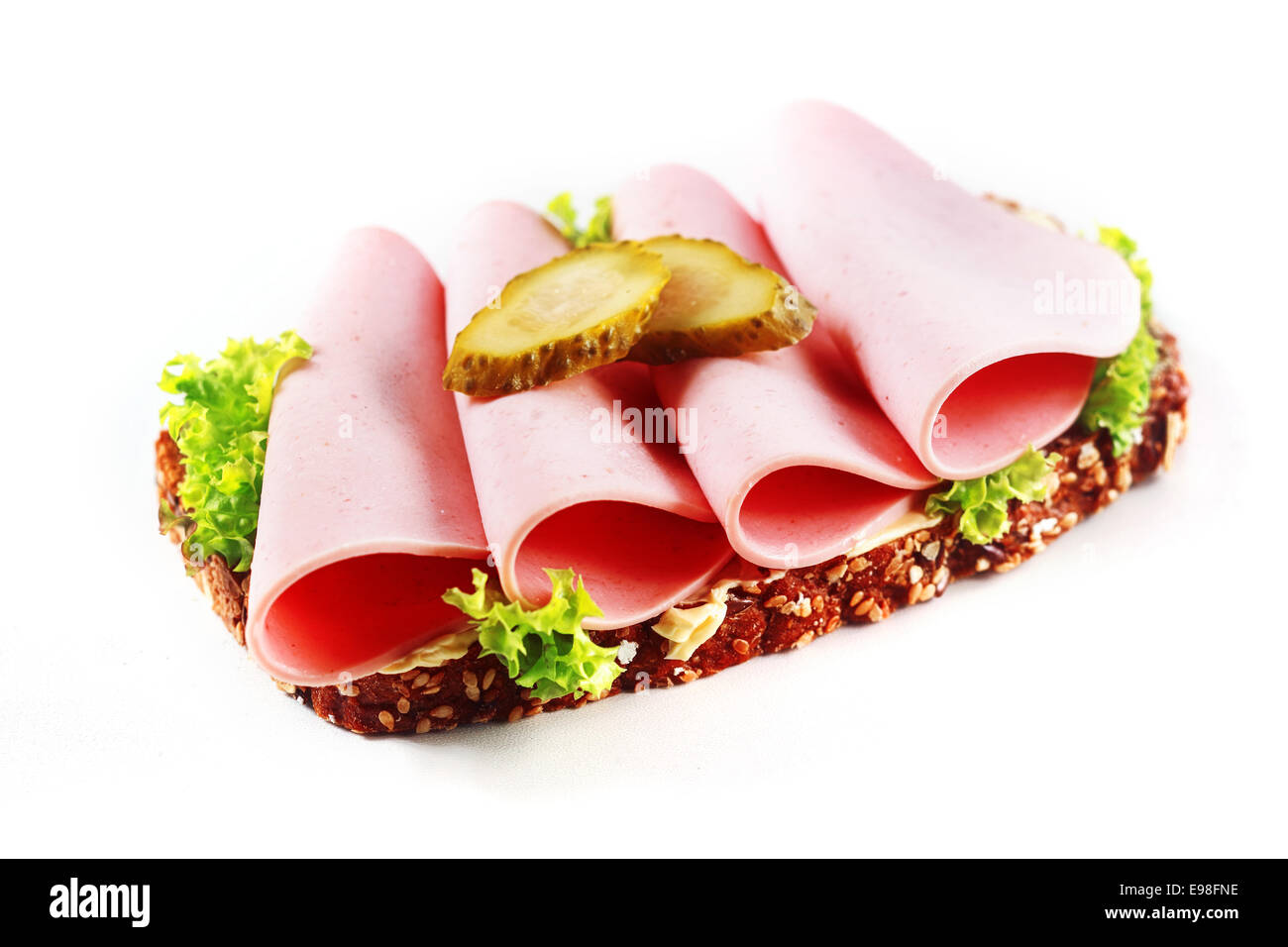 Mortadelle, une saucisse allemande traditionnelle de porc et boeuf, surmontées de cornichon sur un lit de laitue à feuilles fraîches sur un sandwich pain complet sedd isolated on white Banque D'Images