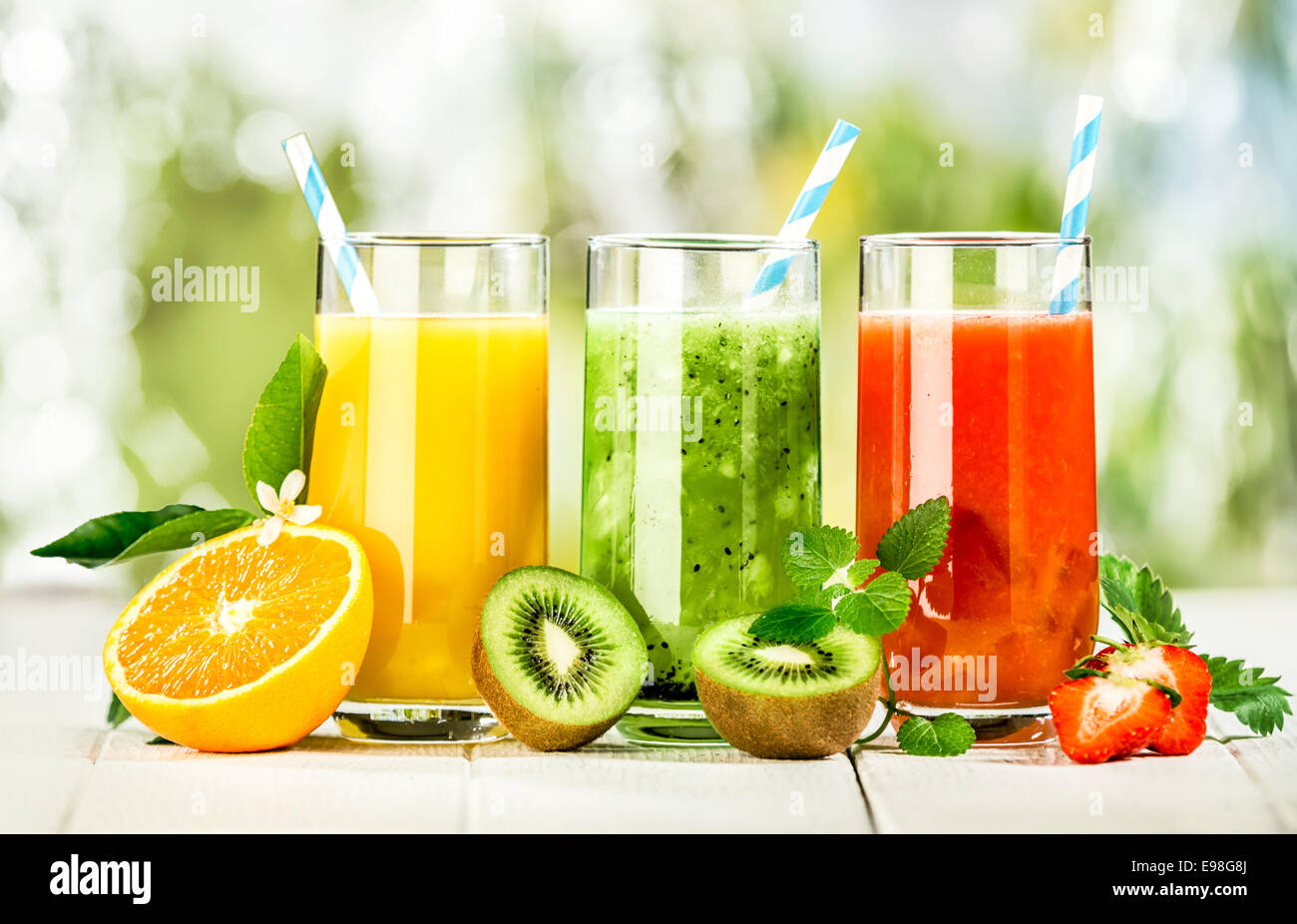 Gamme de délicieux jus de fruits frais servis dans des grands verres fabriqués à partir de liquidized orange, les kiwis avec la menthe poivrée, et les fraises de l'été en bonne santé, riche en vitamines Banque D'Images
