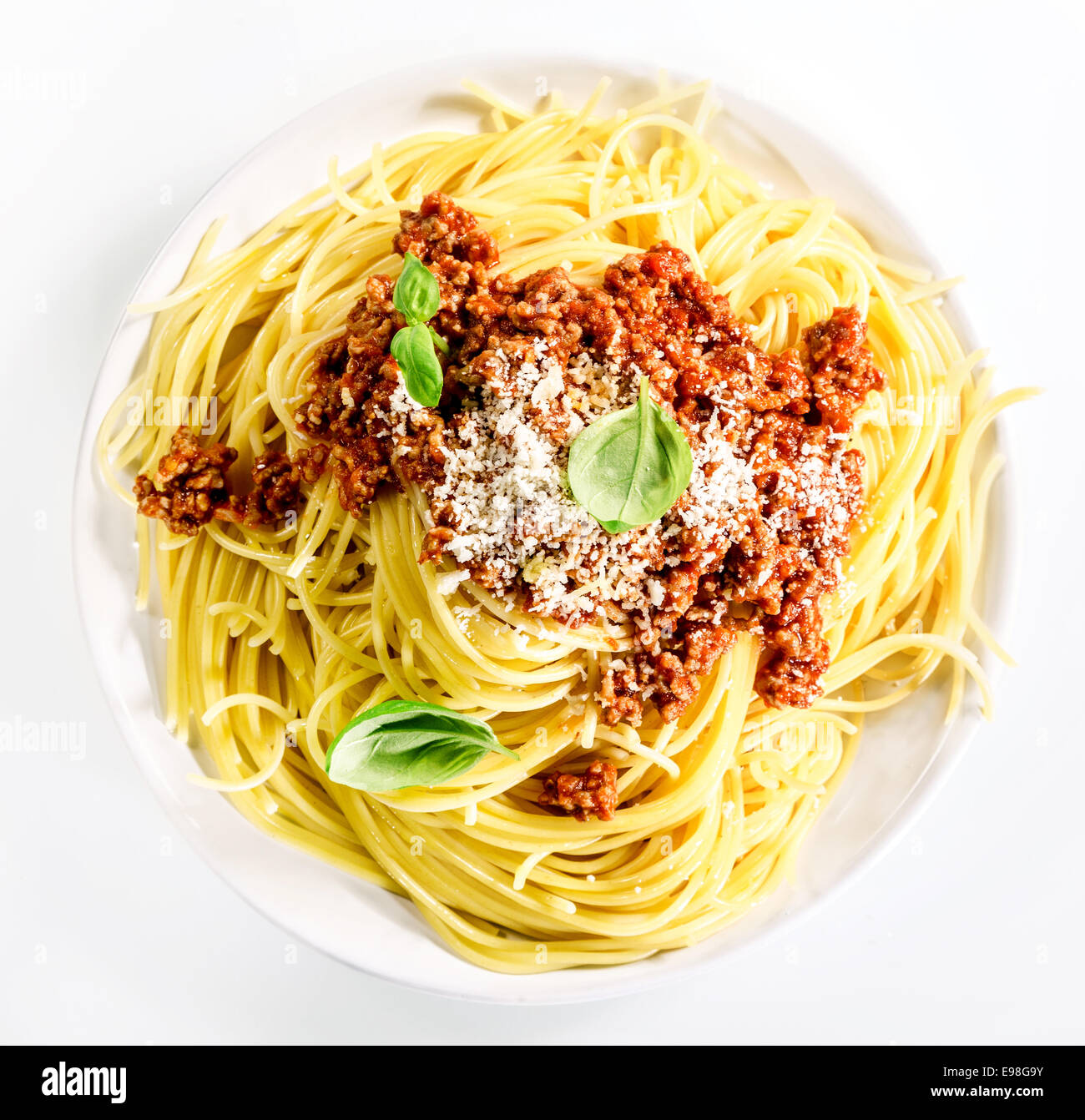 Au service de l'Italien de spaghettis à la bolognaise avec du boeuf haché, de parmesan et de feuilles de basilic frais pour une savoureuse cuisine méditerranéenne traditionnelle, overhead view on white Banque D'Images