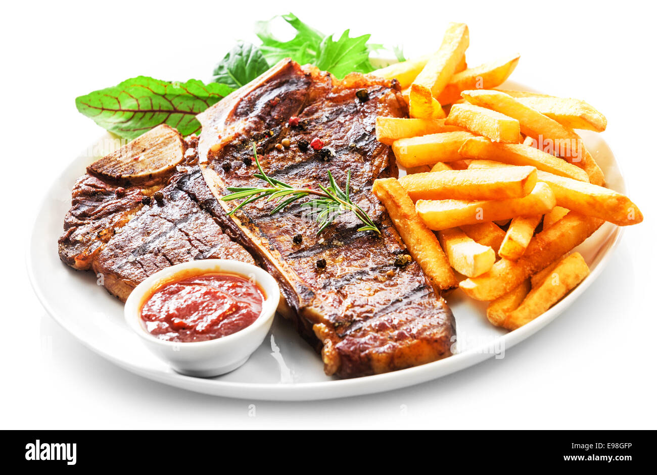 L'aloyau grillé tendre ou t-bone steak servi avec des frites dorées et salade d'herbes fraîches accompagnées d'un barbecue ou sauce ketchup aux tomates Banque D'Images