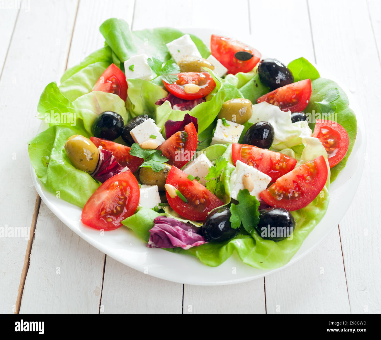 Fresh Salade méditerranéenne à la feta, olives, laitues, fines herbes et tomates arrosées d'huile d'olive pour un régime alimentaire sain, Banque D'Images