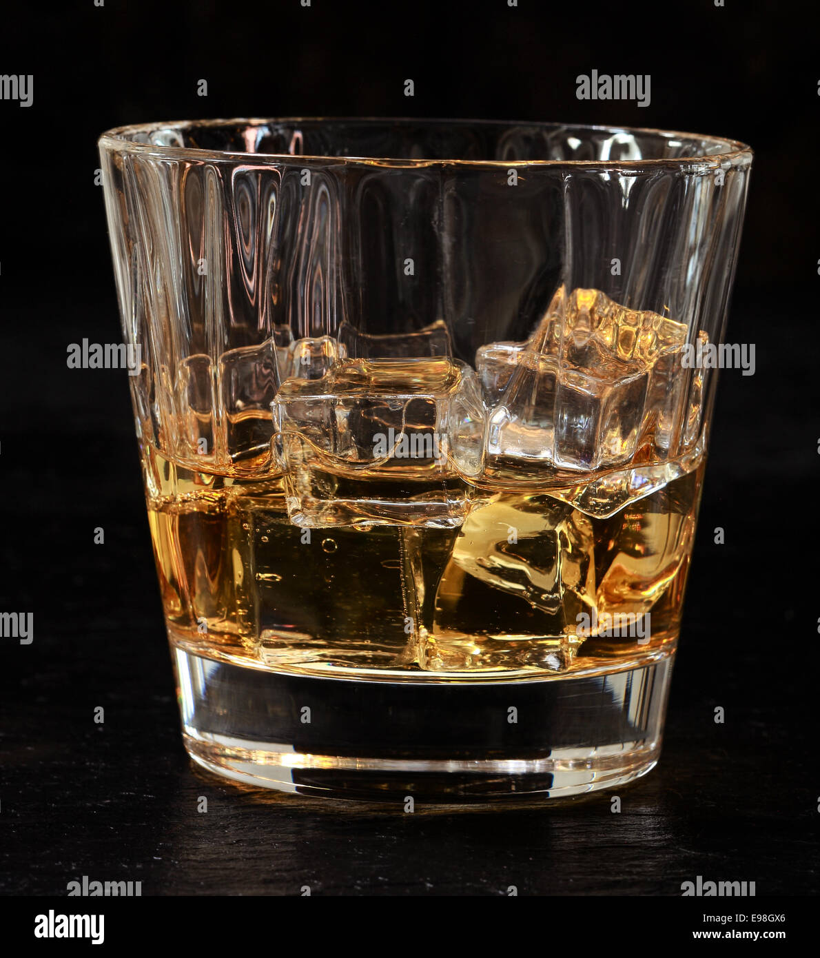 Verre de whiskey on the rocks servi bien frais sur des glaçons pour une boisson rafraîchissante au bar, vue rapprochée sur noir Banque D'Images