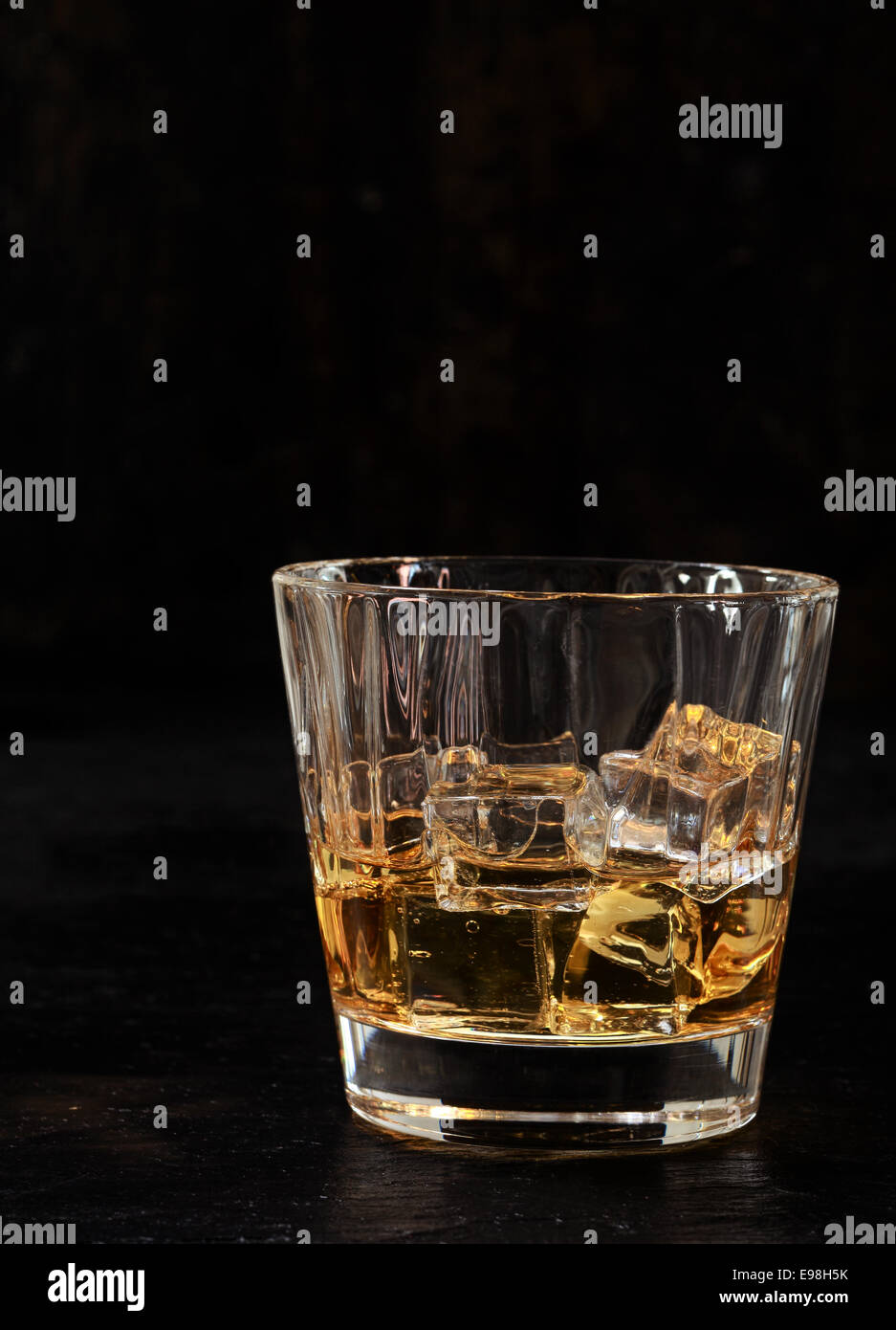 Bourbon glacé ou de whisky dans un verre Tumbler sur un fond sombre avec copyspace verticale Banque D'Images