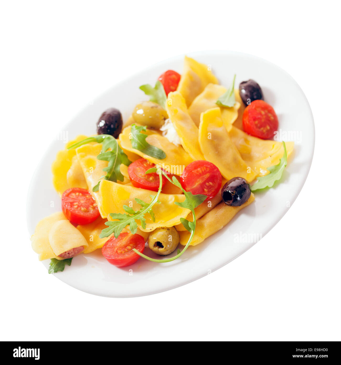 Raviolis italiens colorés avec salade de tomates fraîches, de fusée ou de feuilles de roquette, et d'olives noires et vertes pour un savoureux hors-d'isolated on white Banque D'Images