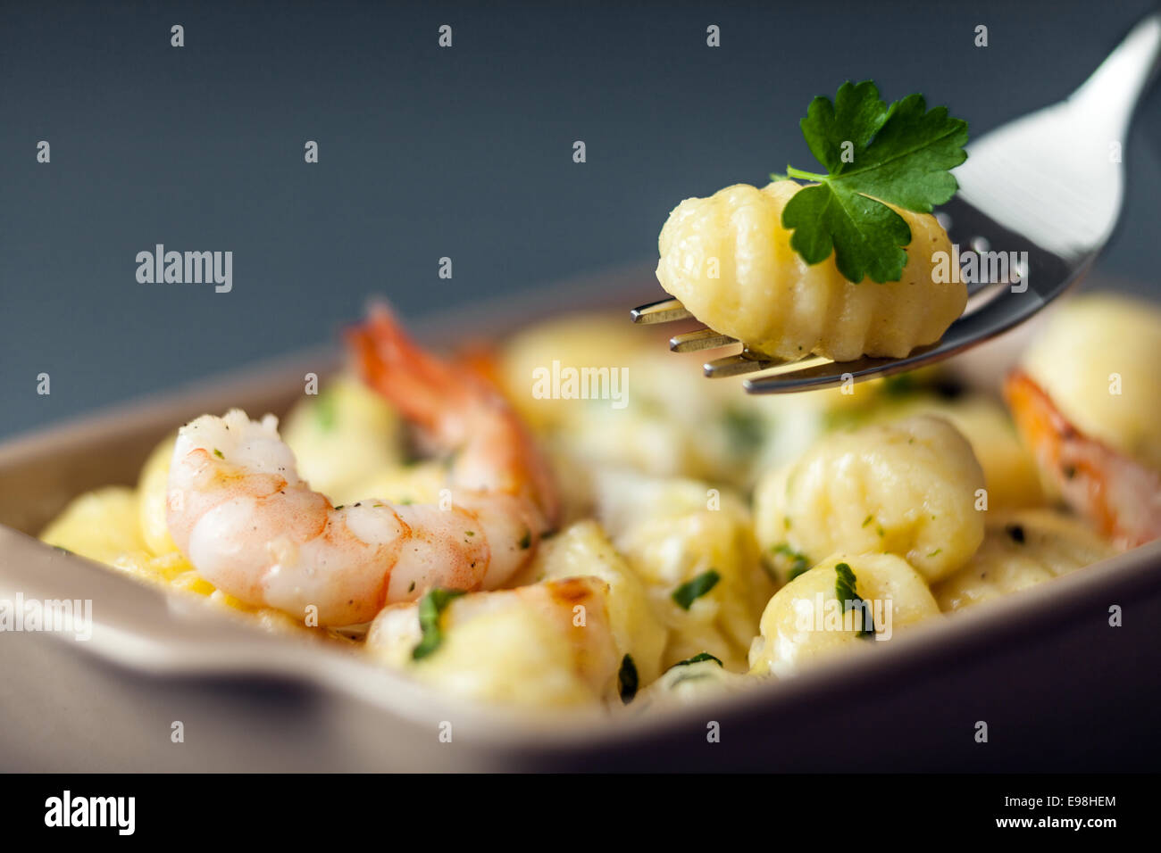 Des gnocchi italiens, ou des boulettes de pâte faite avec de la semoule, aux gambas ou crevettes pour une délicieuse cuisine de fruits de mer avec une boulette sur une fourchette avec selective focus Banque D'Images