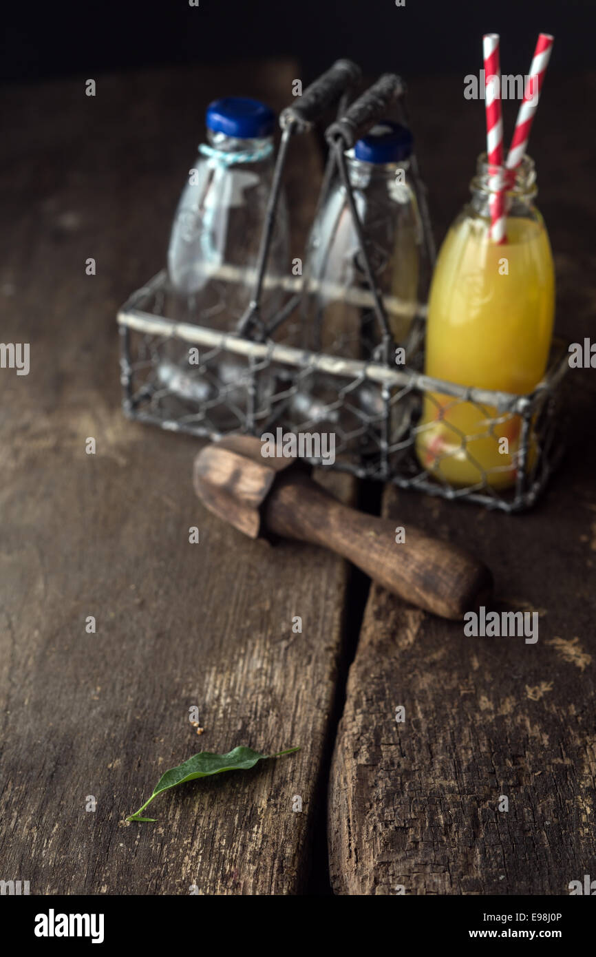 Les bouteilles de jus de fruits dans le bac sur la table en bois. Banque D'Images