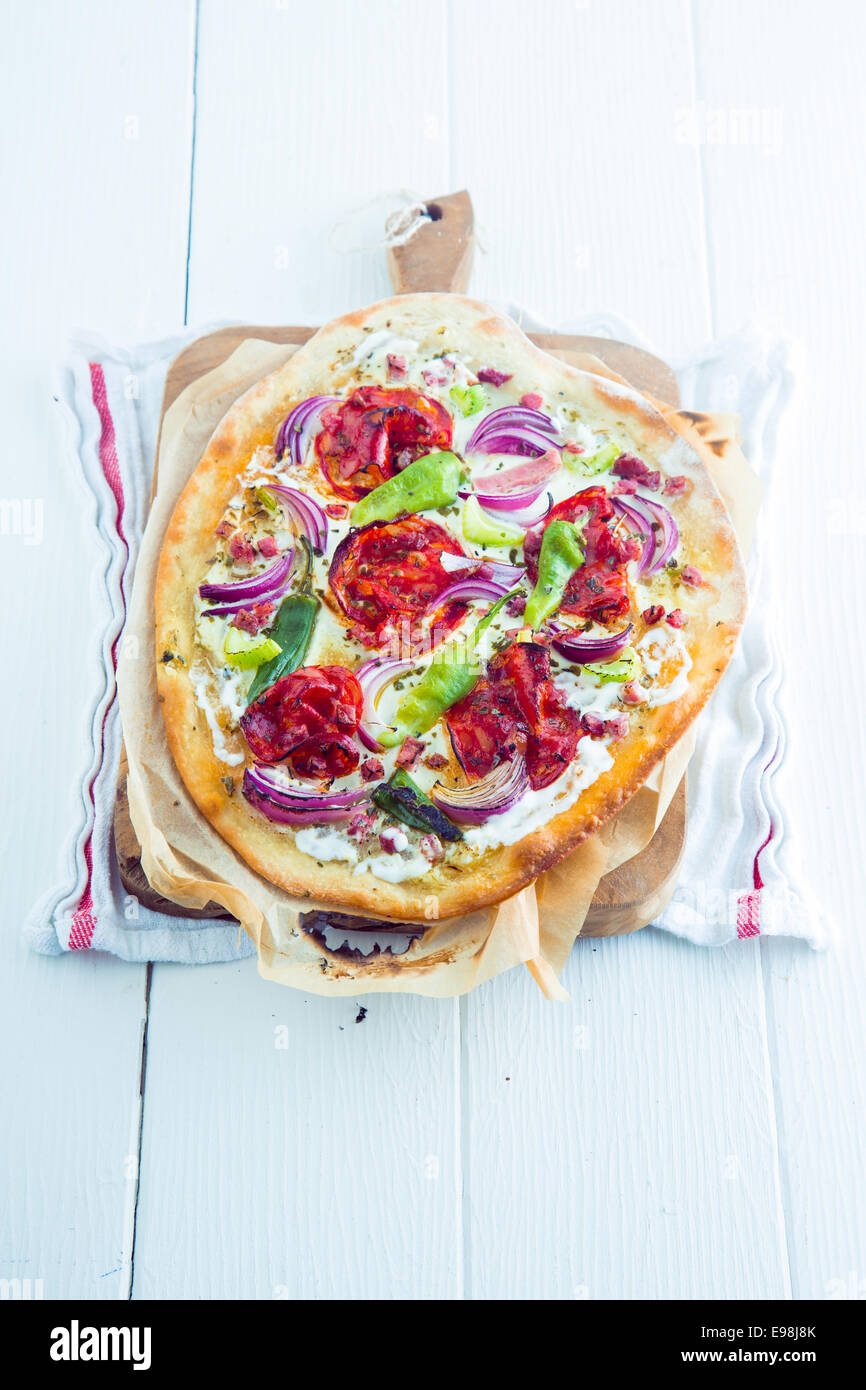 Tarte flambée alsacienne traditionnelle avec une fine croûte feuilletée, lardons ou de lardons, de fromage ou de crème fraîche, les herbes, la tomate et Banque D'Images