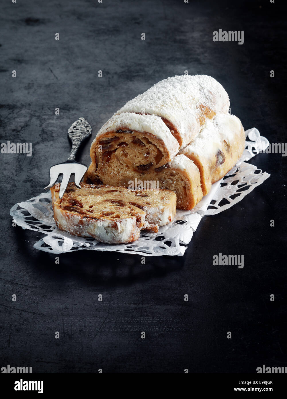 Panettone pain fraîchement mis en balles pour la saison de Noël , une spécialité recette pour un pain sucré avec des épices et des fruits, servi en tranches avec une fourchette et copyspace sur fond sombre Banque D'Images