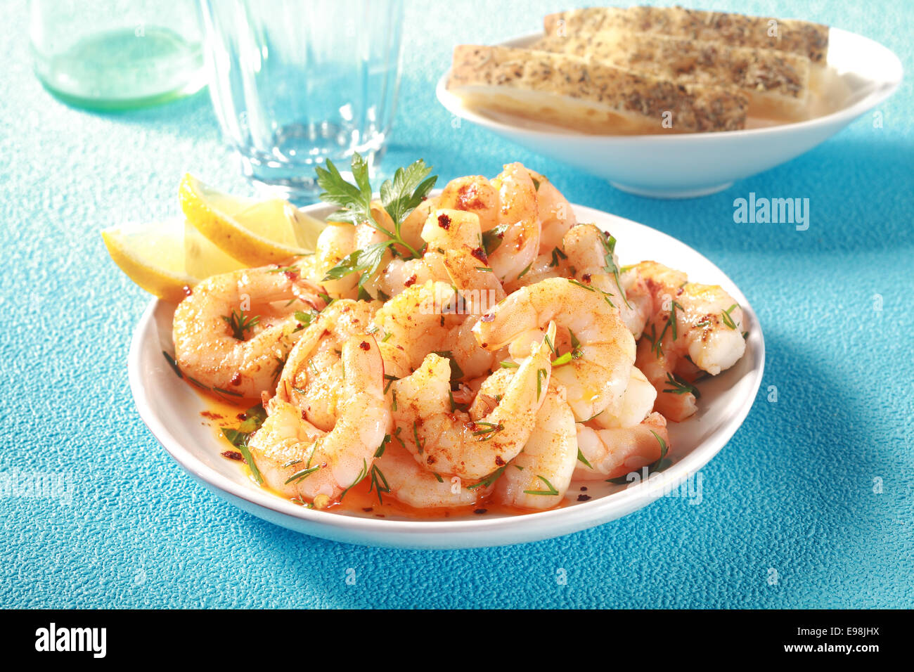 Démarreur de fruits de mer gastronomique de gambas ou Crevettes roses grillées assaisonnées avec des herbes fraîches et d'huile d'olive et garni de tranches de citron sur un tableau bleu Banque D'Images