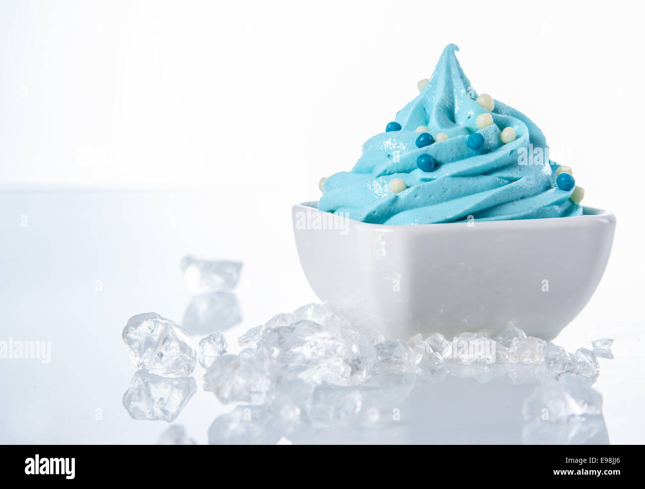 Délicieux Yogourt glacé de couleur blanche sur le bol avec des cubes de glace sur les côtés. Isolé sur blanc. Banque D'Images