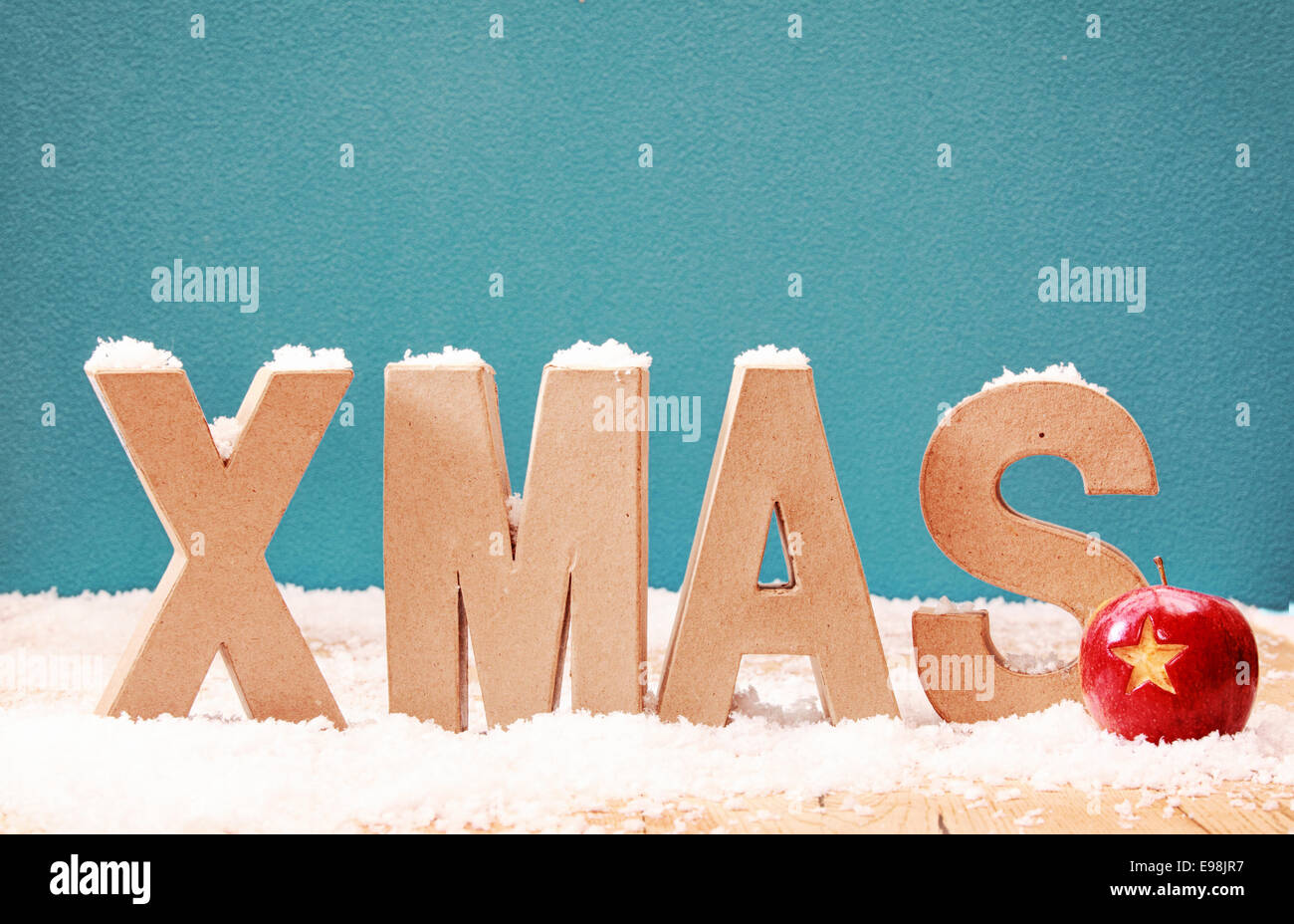 Neige de Noël arrière-plan avec lettres alphabet couverts dans une mince couche de neige contre un hiver cool blue avec un fond rouge babiole coloré décoré avec une étoile, copyspace pour votre message de Noël Banque D'Images