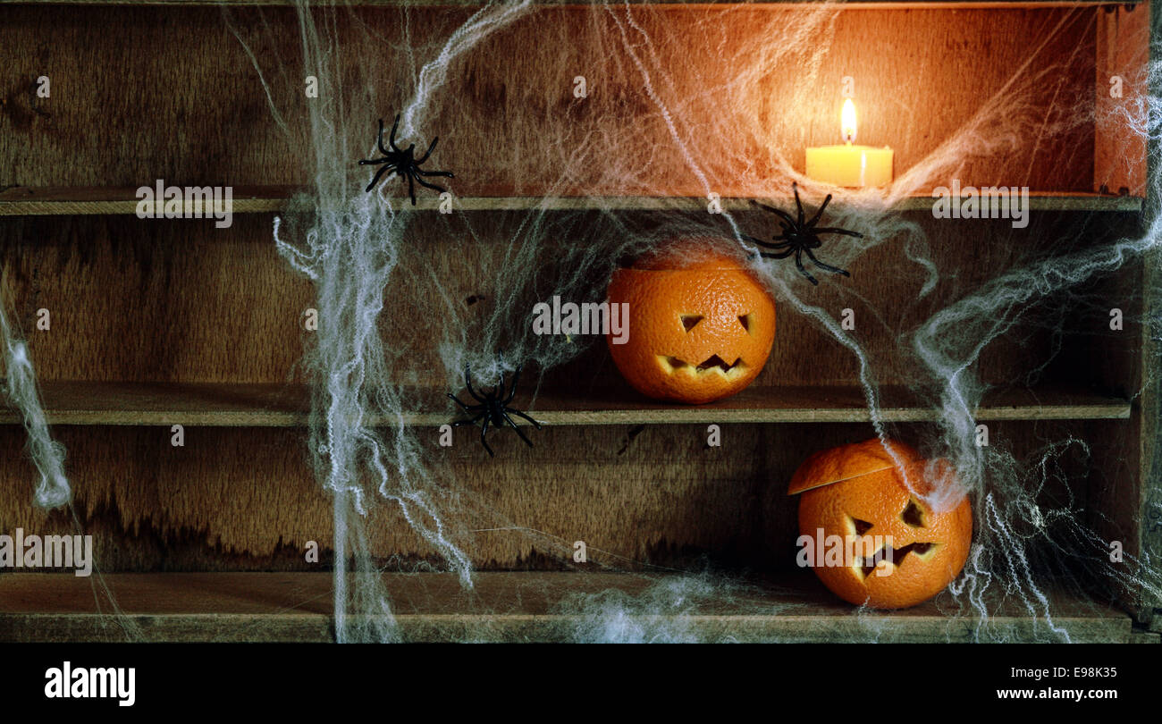 Deux Halloween Jack o lanterne sculptée à partir d'Oranges et d'araignées et des Araignées avec bougie allumée sur des étagères Banque D'Images