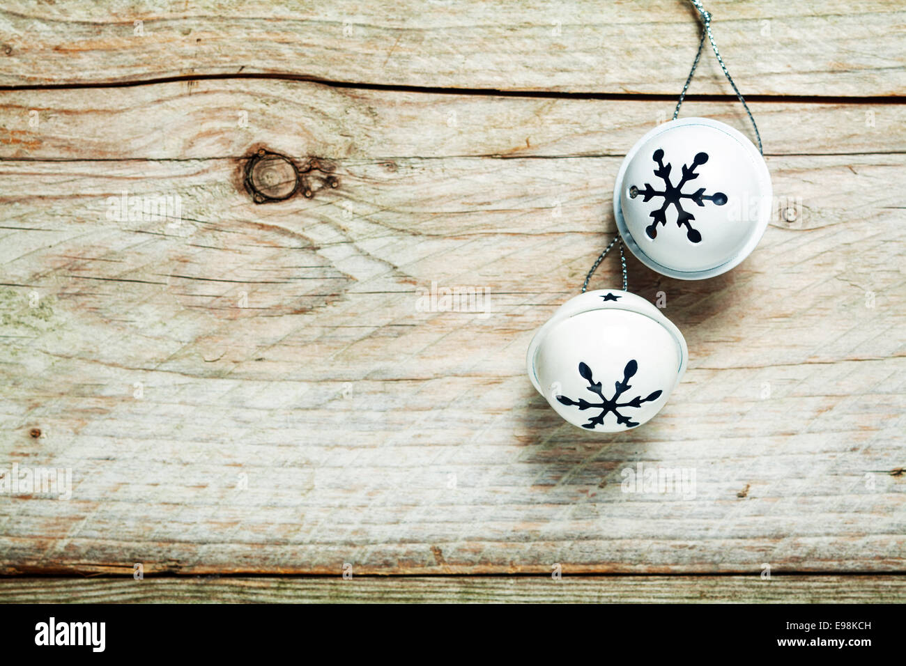 Tour métallique silver Christmas Bells contexte accroché sur un vieux mur en bois avec des fissures et des nœuds et copyspace pour vos souhaits de saison Banque D'Images