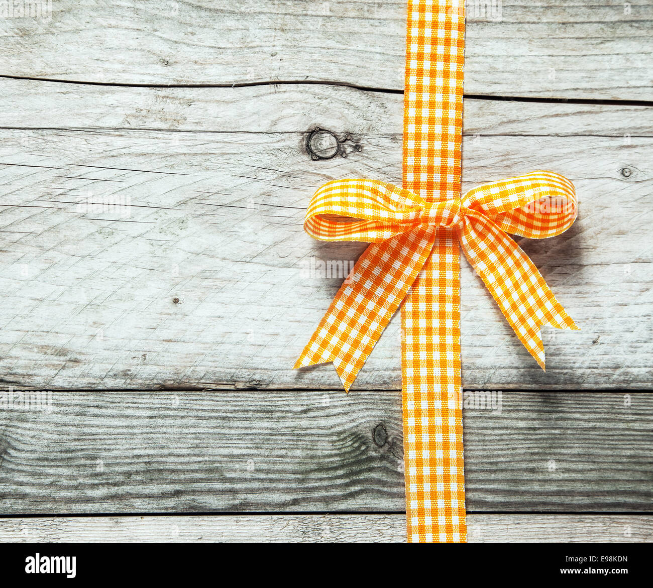 Orange et blanc coloré ruban rustique de fête et de décoration de proue un fond de vieux bois patiné craquelé avec copyspace pour votre message d'anniversaire ou Noël saison Banque D'Images