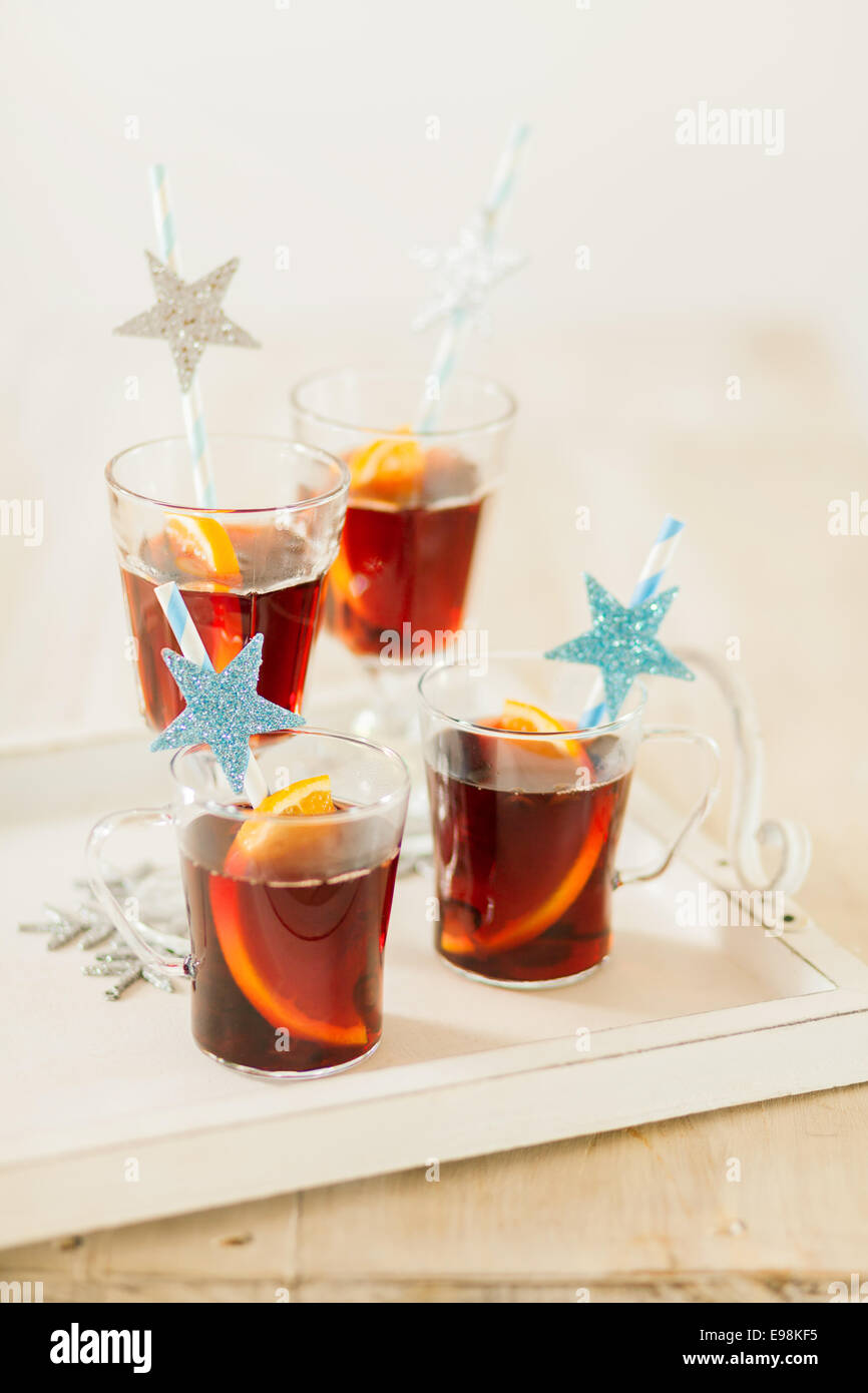 Quatre verres de punch de Noël avec des épices et des tranches d'orange servi avec des pailles décoratives avec blue glitter Banque D'Images