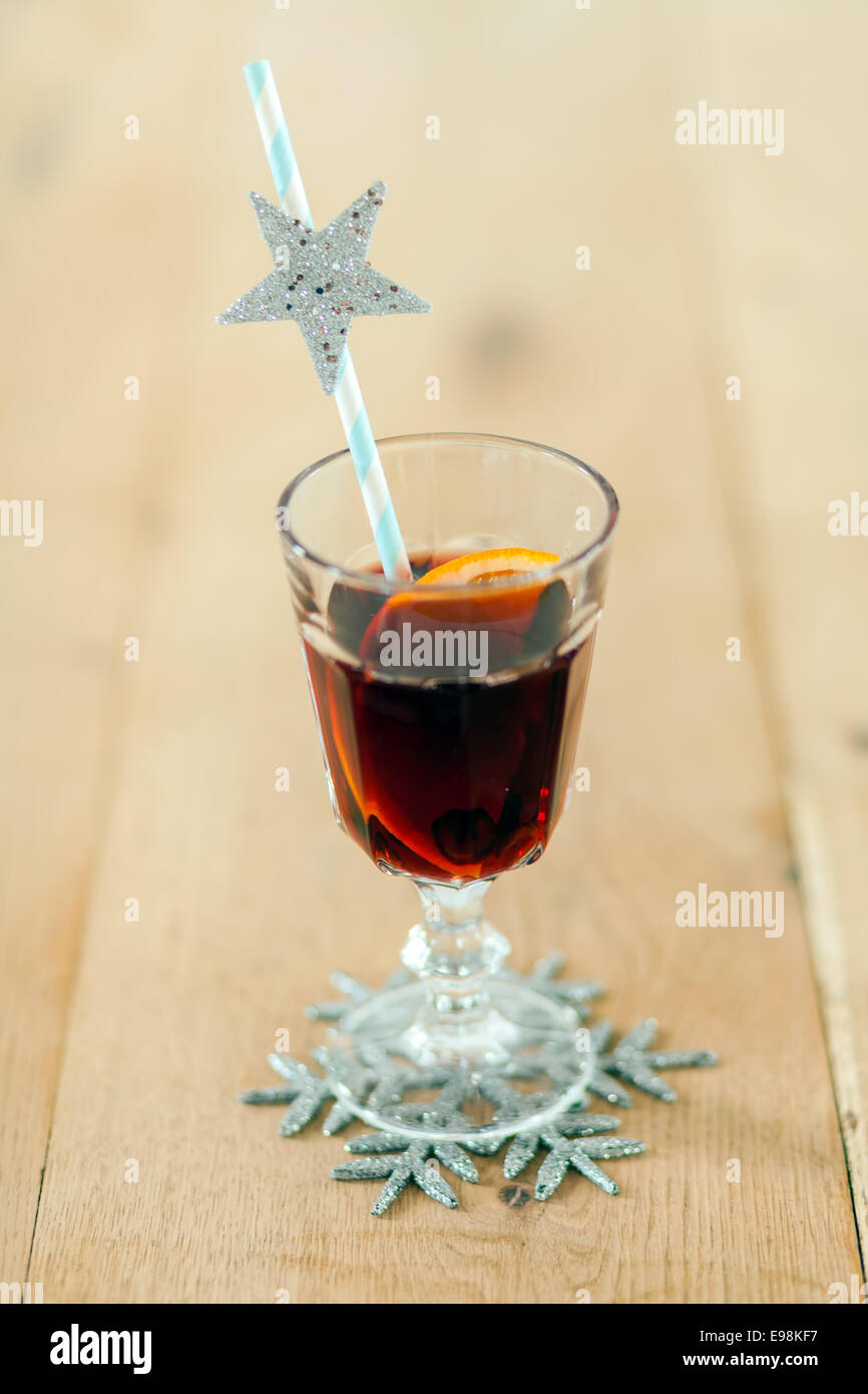 Verre de vin rouge ou vin chaud de Noël gluhwein assaisonné d'épices et d'orange servi avec une paille décorée d'une glitter bleu et snowflake coaster Banque D'Images