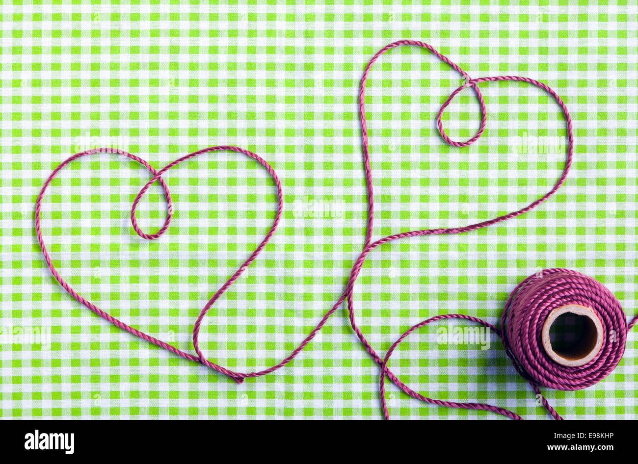 Coeur dessiné avec purple thread via un tag sur un motif de tissu à carreaux Banque D'Images