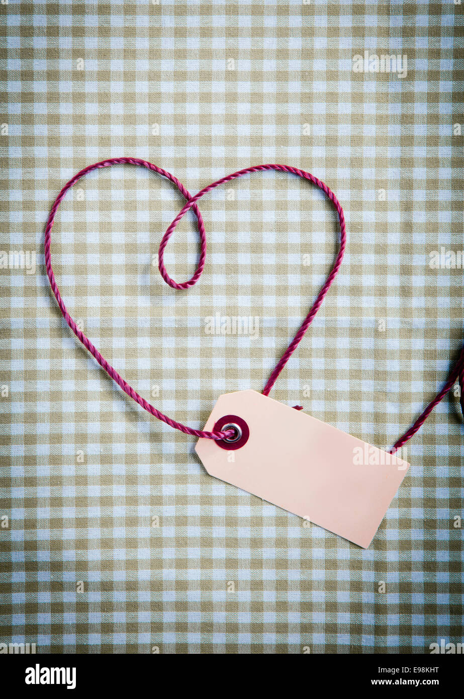 Coeur dessiné avec purple thread via un tag sur un motif de tissu à carreaux Banque D'Images