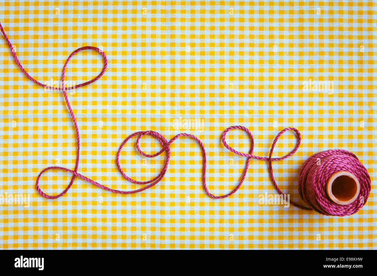 Le mot amour tiré de pourpre et d'un fil tissu vérifié l'arrière-plan. Banque D'Images