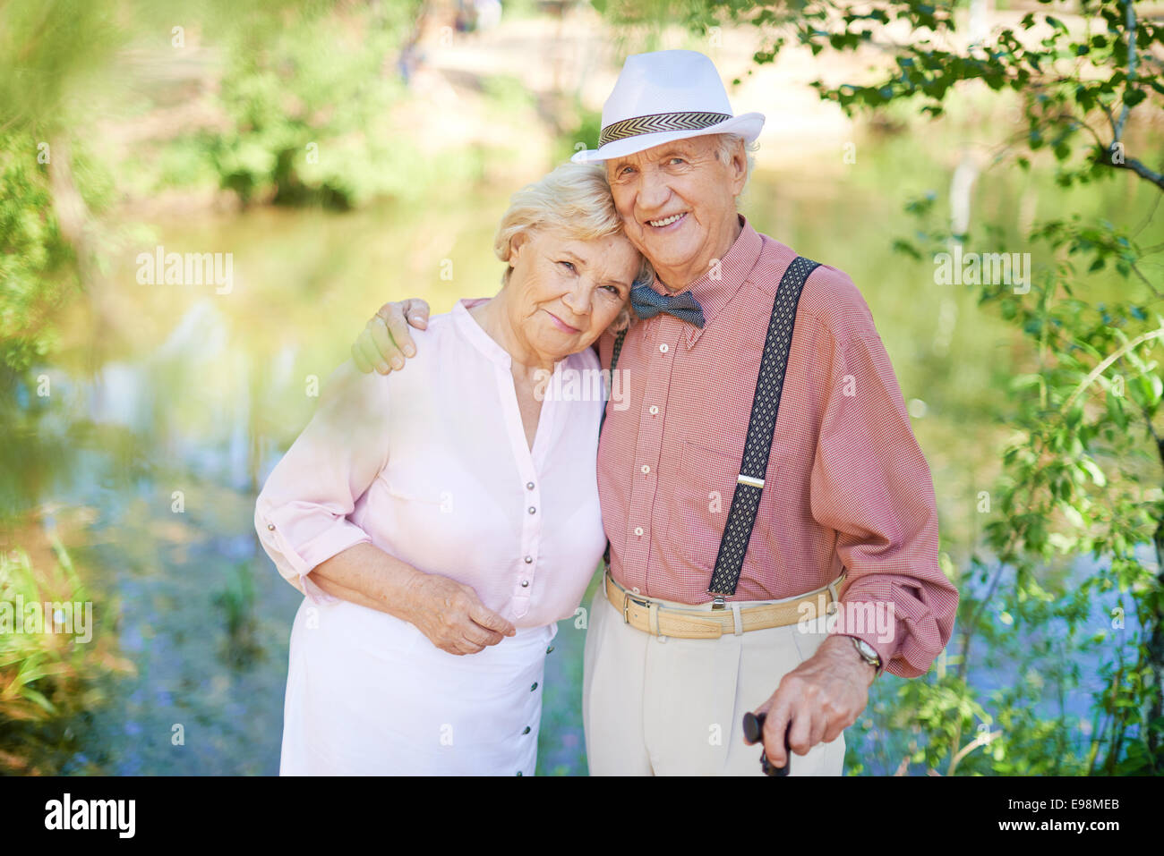 Happy senior couple in smart casual looking at camera en milieu naturel Banque D'Images