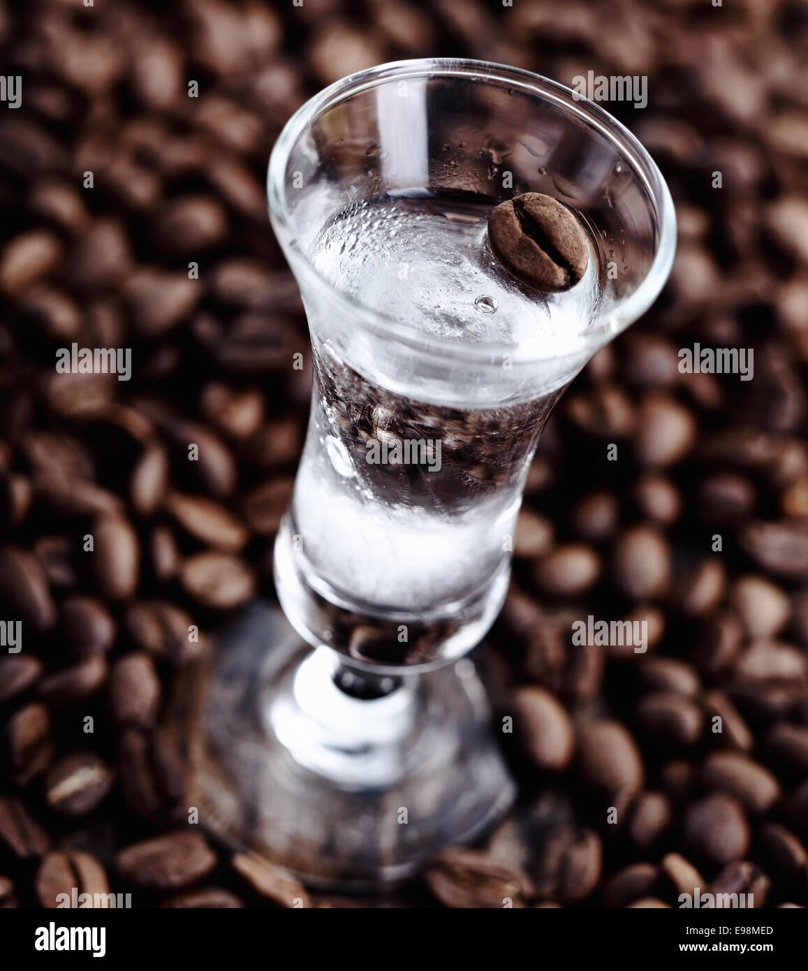 Café sambuca claire dans un grand verre entouré de haricots en grain Banque D'Images