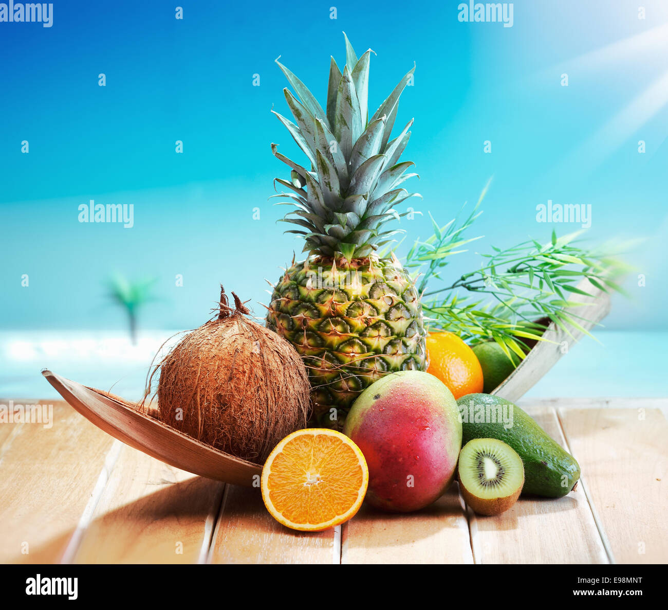 Fruits frais sur la plage à une plate-forme en face d'une île avec un Palm. Un assortiment de fruits tropicaux, Ananas, orange ou d'ananas, citron vert, mangue et avocat. Banque D'Images