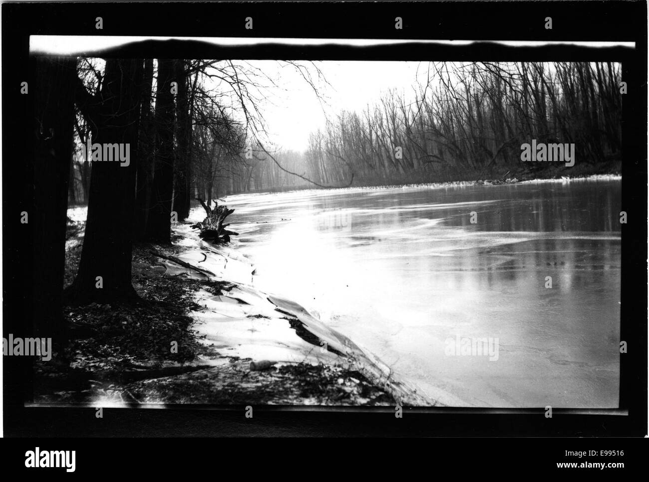 Photographie d'une vieille rivière complètement gelée, datant d'environ 1912. L'image montre la surface glacée de la rivière, avec le paysage environnant probablement recouvert de neige, soulignant les conditions hivernales rigoureuses. Cette photographie historique offre un aperçu des changements saisonniers et des conditions environnementales du début du XXe siècle. Banque D'Images