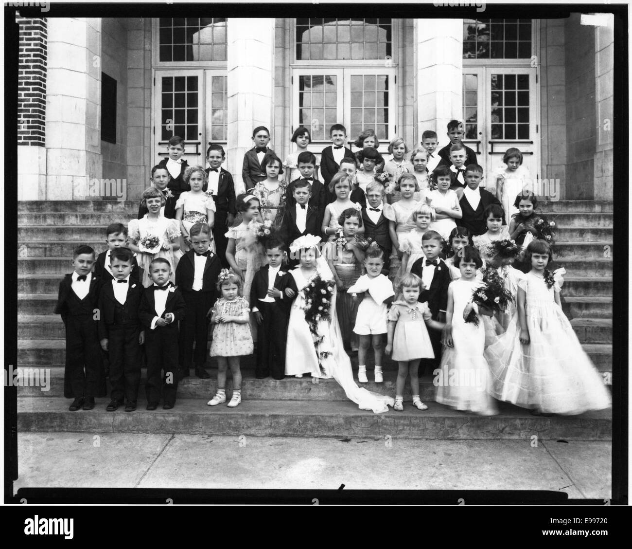 Cette photographie représente un mariage de Tom pouce, un événement populaire du début du XXe siècle où des enfants habillés en mariées et mariés reconstituaient une cérémonie de mariage. L'événement a souvent été mis en scène à des fins de divertissement, symbolisant l'innocence et le jeu d'enfance. Banque D'Images Cette photographie représente un mariage de Tom pouce, un événement populaire du début du XXe siècle où des enfants habillés en mariées et mariés reconstituaient une cérémonie de mariage. L'événement a souvent été mis en scène à des fins de divertissement, symbolisant l'innocence et le jeu d'enfance. Banque D'Images
