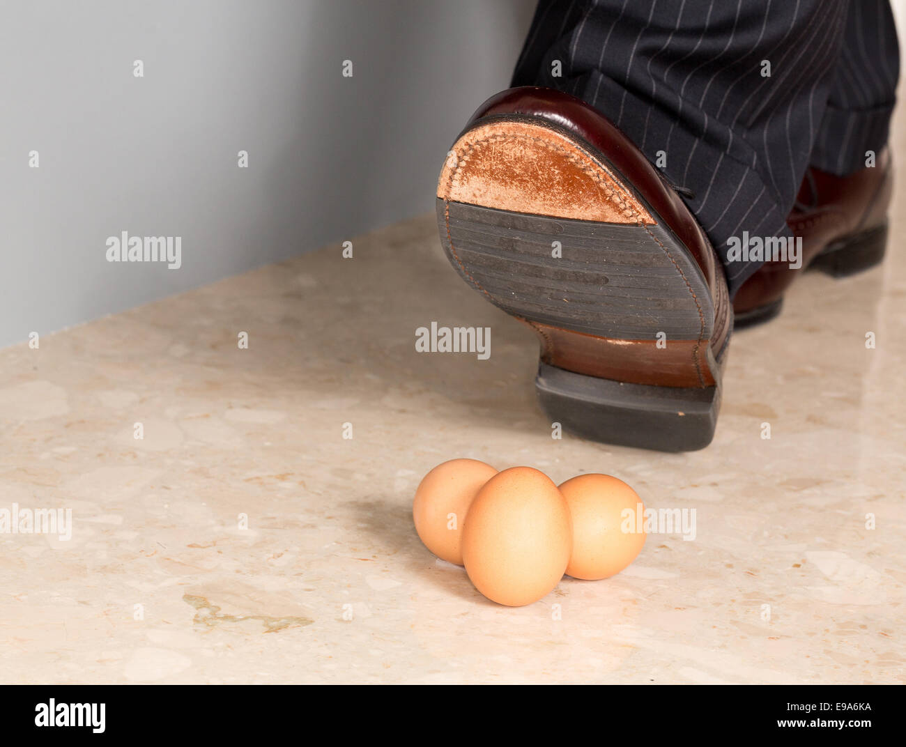 Man's shoe stamping sur trois oeufs Banque D'Images