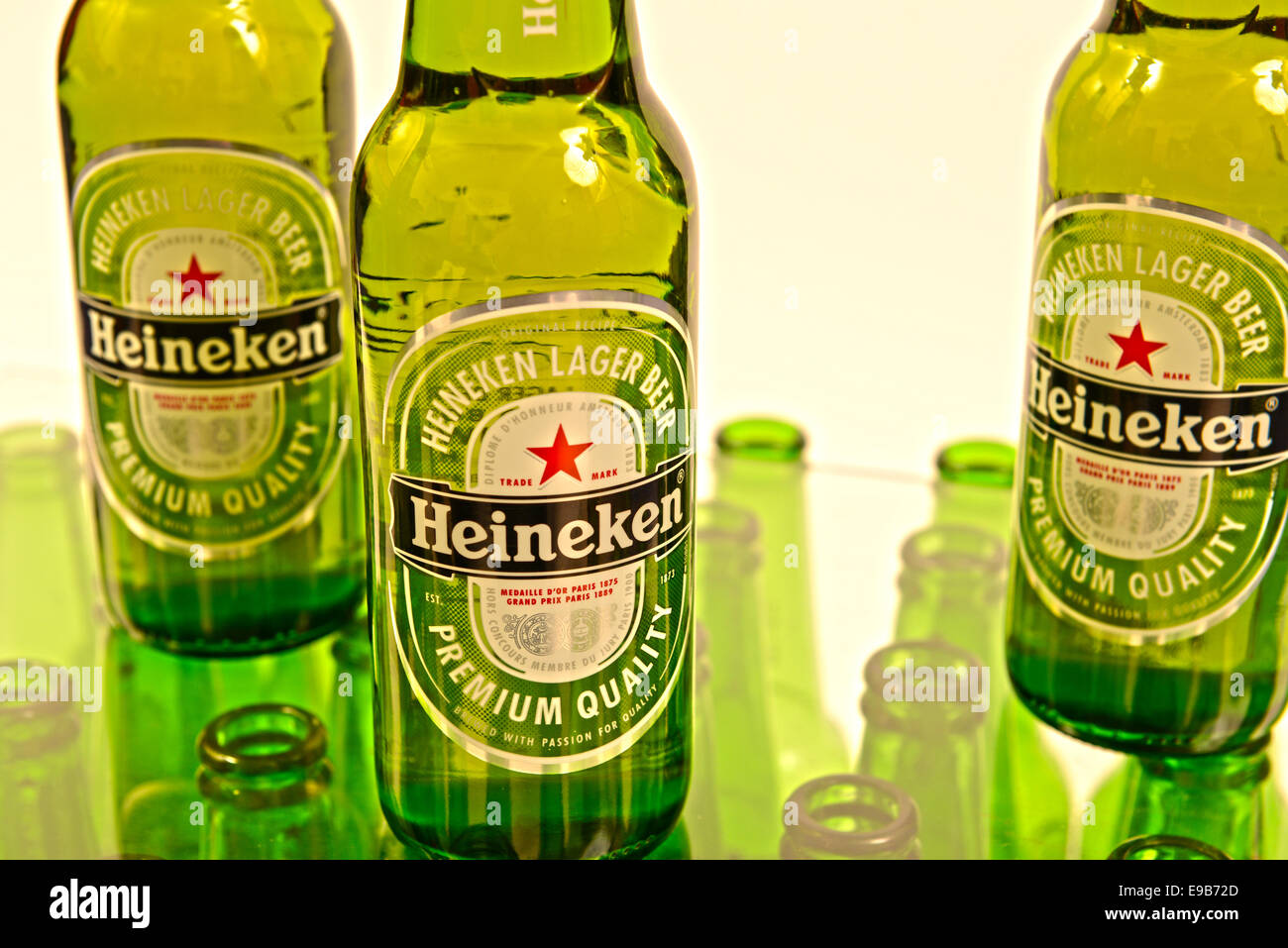 Trois bouteilles de Heineken avec des rangées de bouteilles en verre en