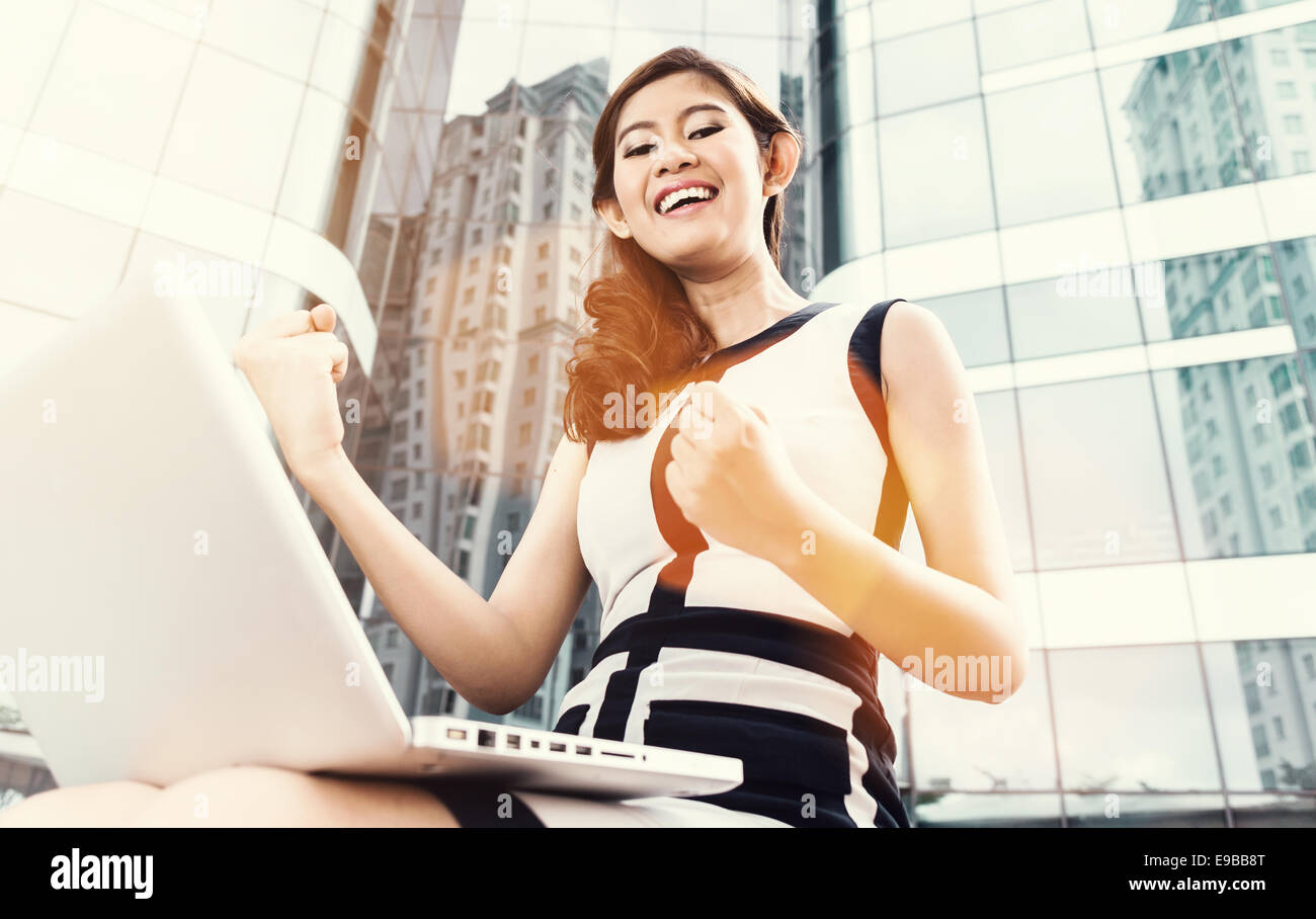 Asian business woman outdoors with laptop om/de réflexion skyline Banque D'Images