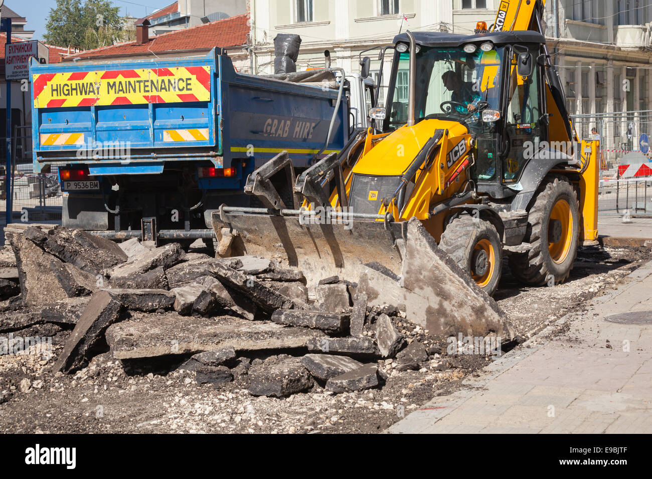 Ruse, Bulgarie - 29 septembre 2014 : Travaux routiers. L'entretien des routes, l'homme en jaune tracteur supprime les anciennes en asphalte et loa Banque D'Images