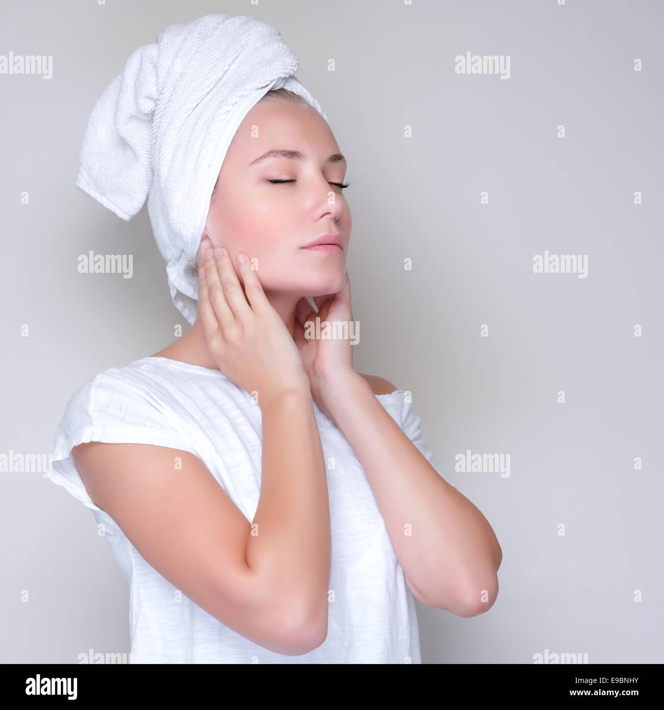 Portrait de mignon femelle avec les yeux fermés et towel on head, studio shot, l'application de crème visage Banque D'Images