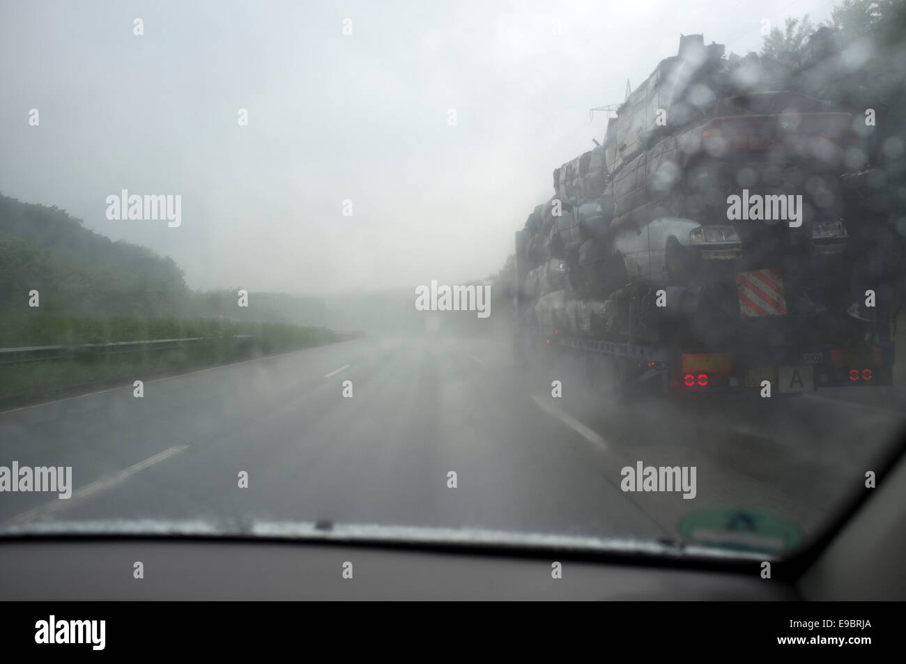 Passant d'un camion transportant des voitures rebutés dans Heavy Rain sur l'autoroute A9 au sud de Munich, Bavière, Allemagne. Banque D'Images