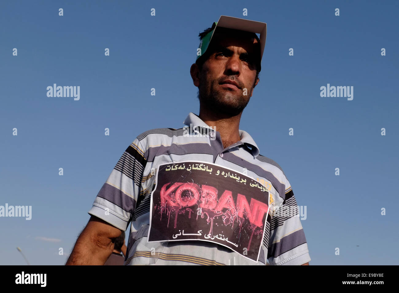 Un kurde porte un gros autocollant apposé sur sa chemise et portant la mention « Kobani » lorsqu'il participe à une manifestation devant le siège de l'ONU dans la ville d'Arbil ou d'Irbil pour exiger un soutien international à la ville syrienne de Kobane alors qu'elle tente de résister à un attaque djihadiste mortelle. Nord de l'Irak Banque D'Images