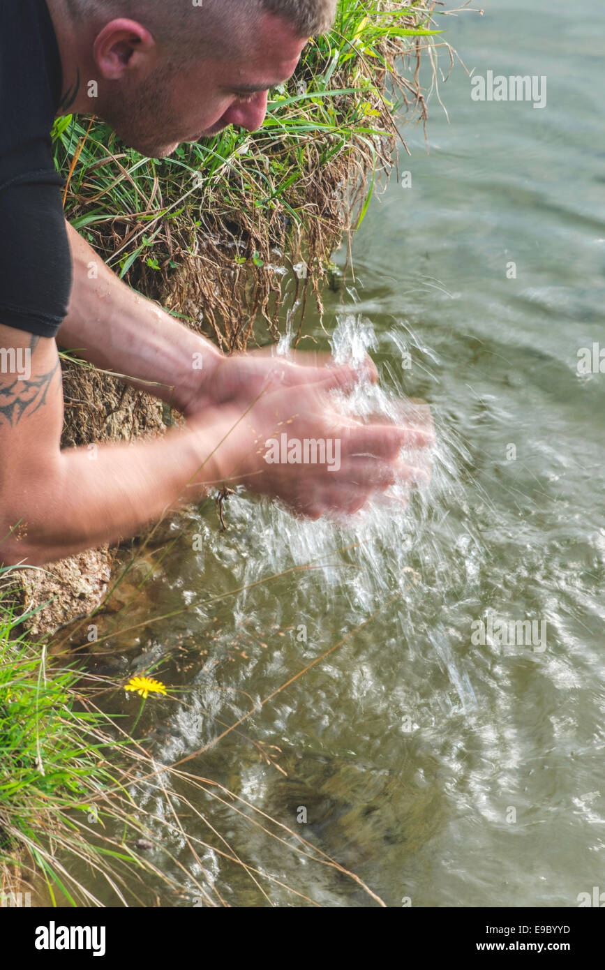 Garçon se laver les mains dans un lac. Close up Banque D'Images