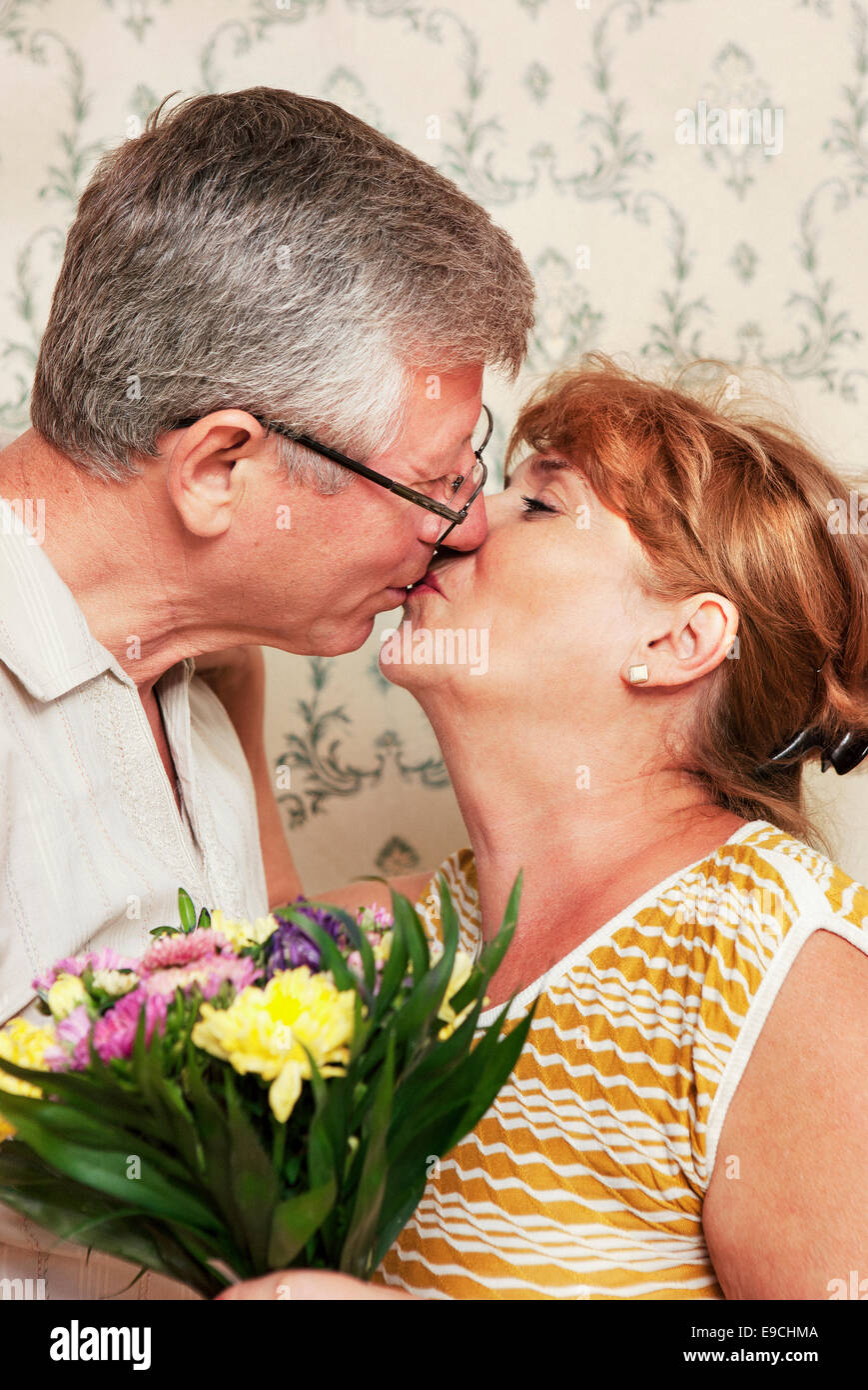 Deux adultes qui s'embrassent et holding bouquet de fleurs Banque D'Images
