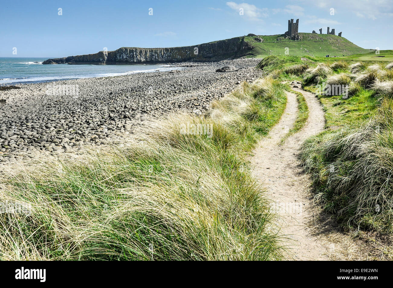 Sentier du littoral menant au château de Dunstanburgh le long de la côte spectaculaire de grosses roches. Banque D'Images