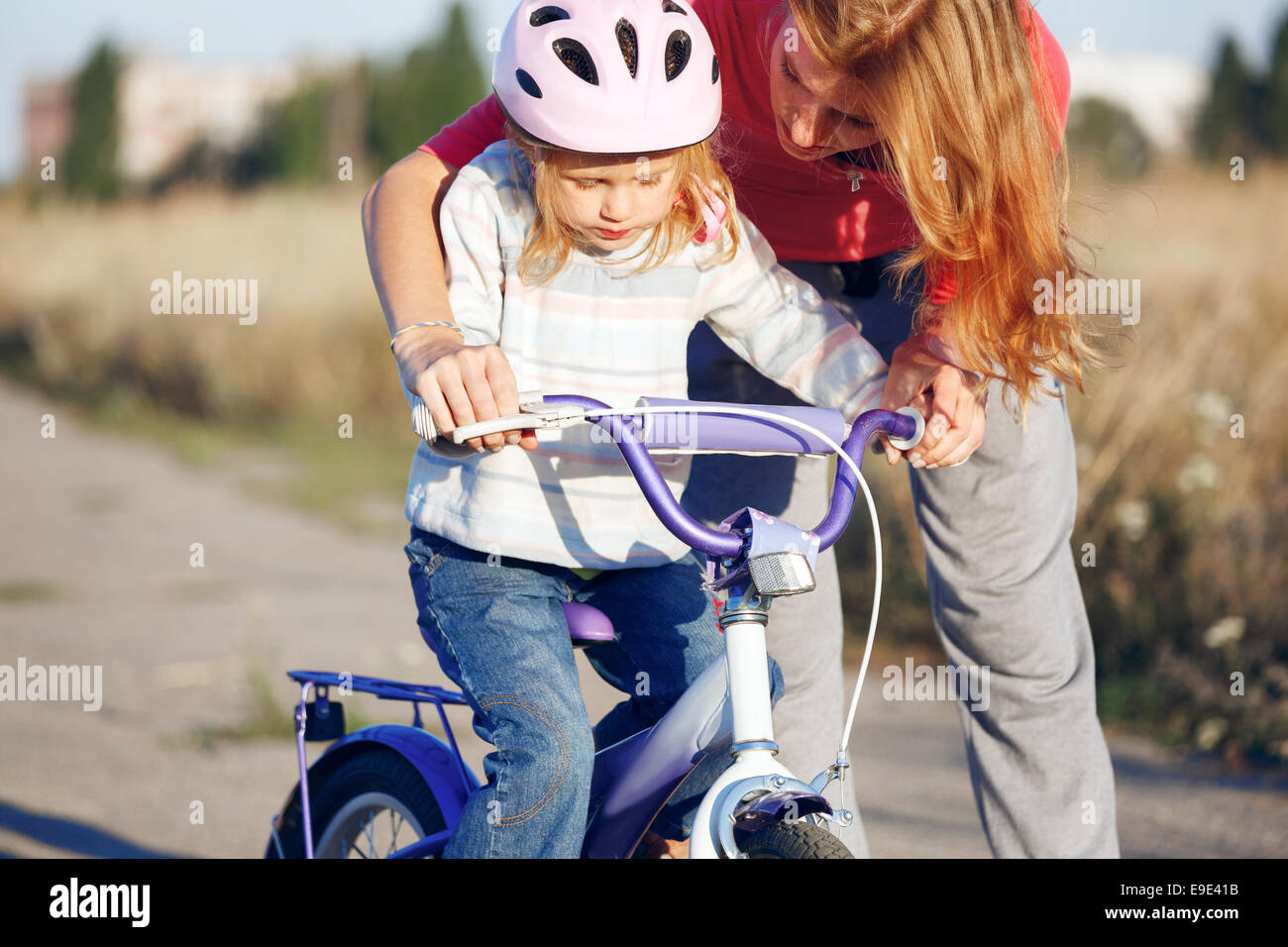 Redhead girl riding bike casque dans l'apprentissage. Banque D'Images