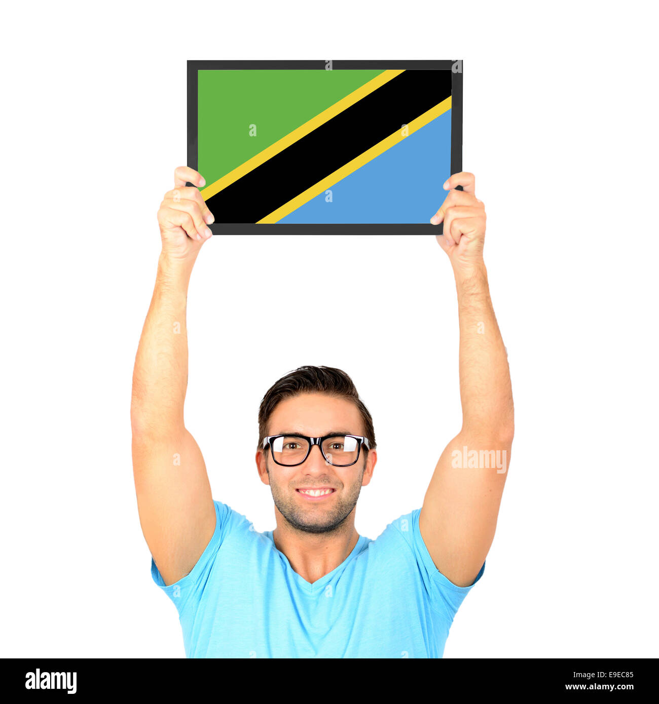 Portrait of a young man holding up conseil occasionnels avec drapeau national de Tanzanie Banque D'Images