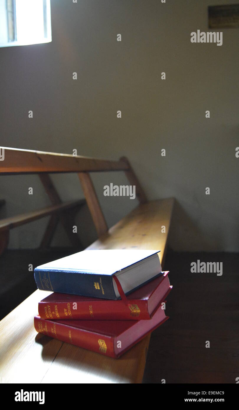 Une pile de livres sur une église pew baigné de lumière naturelle Banque D'Images