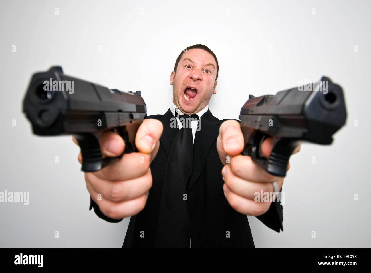 Un homme avec deux canons vêtu d'un costume noir et une cravate tire des  armes à l'appareil photo Photo Stock - Alamy