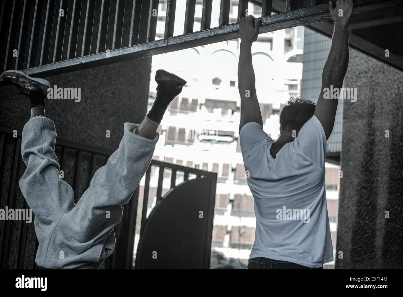 Parkour: Deux jeunes - un pied dans l'air exécutant une béquille l'autre balançant de la rambardes Banque D'Images