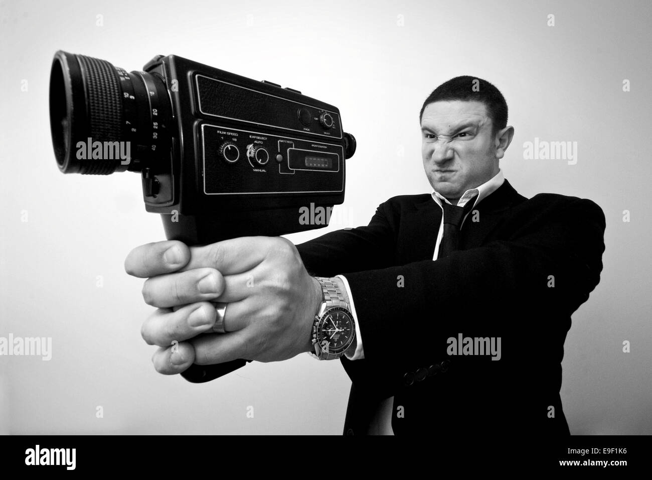 Une photo en noir et blanc d'un homme tenant une caméra vidéo dans une fusillade un fusil poser Banque D'Images
