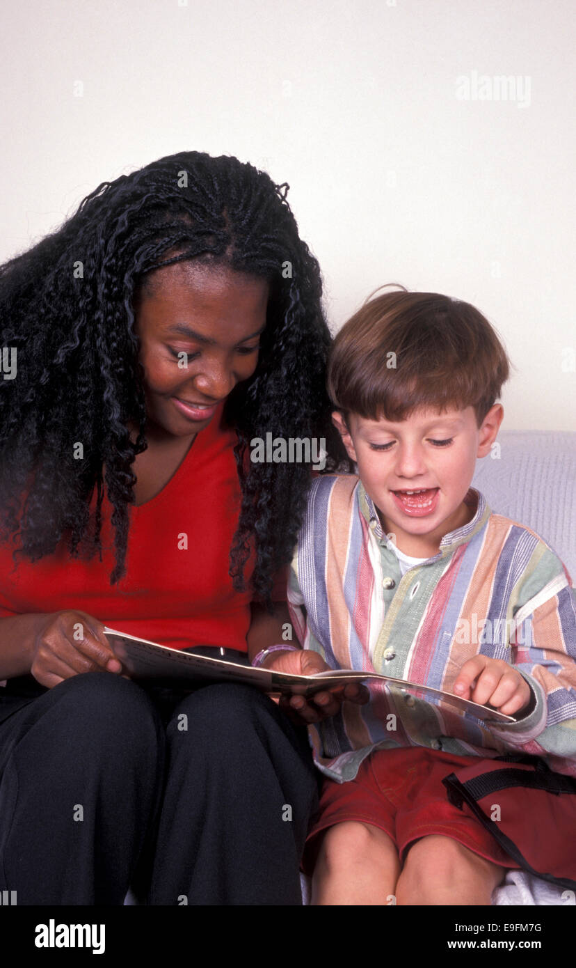Young woman reading to boy Banque D'Images