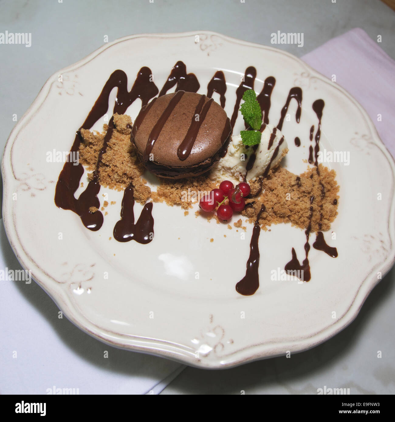 Un dessert, un macaron à la crème glacée, les biscuits hachés, baies et siroup au chocolat. Banque D'Images
