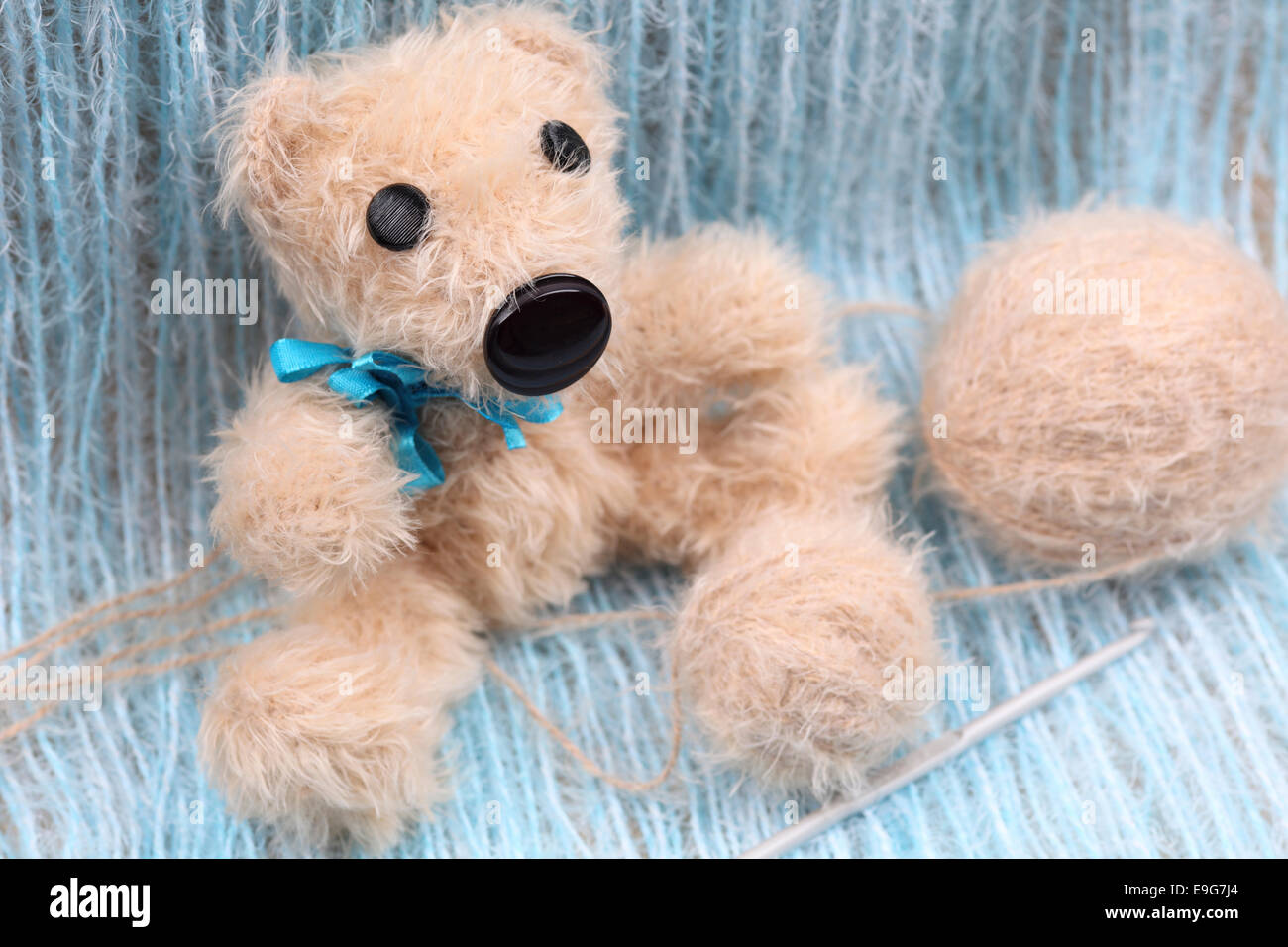 Ours fait main tricot beige avec un fil bleu noeud sur fond threads avec  crochet et pelote de laine Photo Stock - Alamy