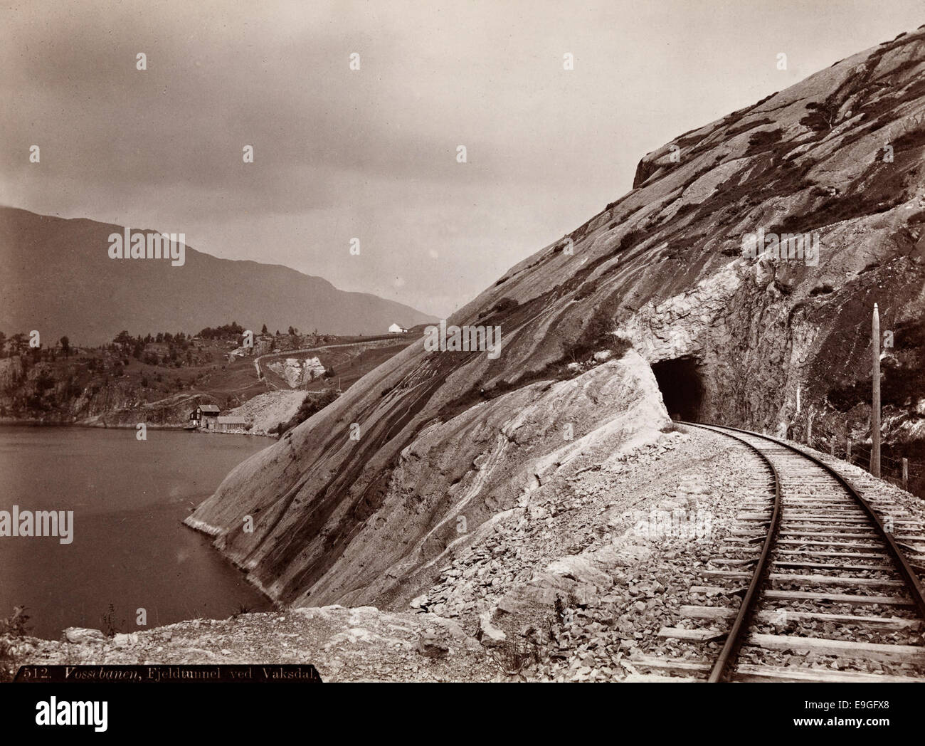 Cette photographie capture le tunnel de Fjeldtunnel à Vaksdal, qui fait partie du chemin de fer Vossebanen à Hordaland, en Norvège. L'image montre le tunnel et les voies ferrées posés contre le paysage montagneux environnant. Banque D'Images