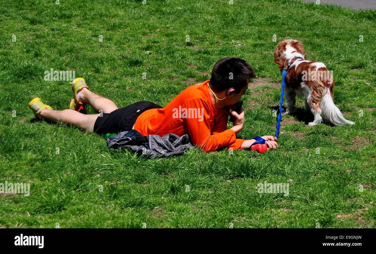 NYC : Jeune homme avec son chien se relâche sur la pelouse en médian centre Riverside Park sur une après-midi de printemps ensoleillé Banque D'Images